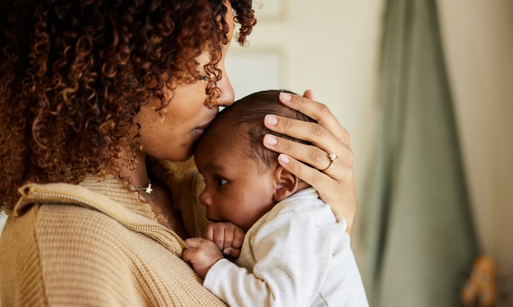 A mother holds her baby boy and kisses his head 