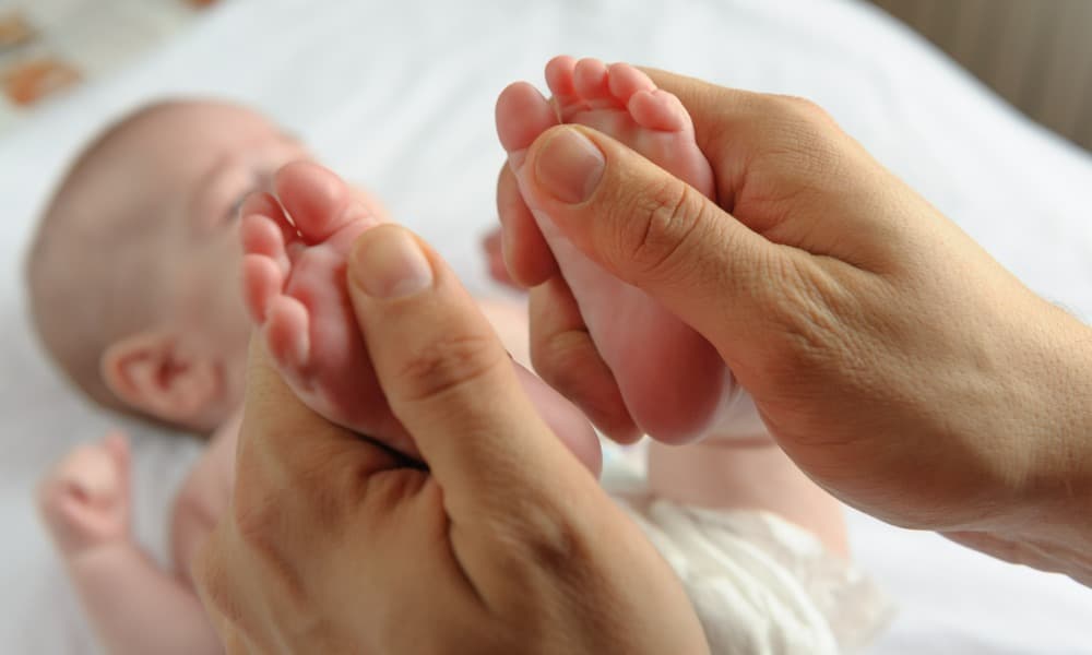 A mother doing reflexology on a baby’s feet