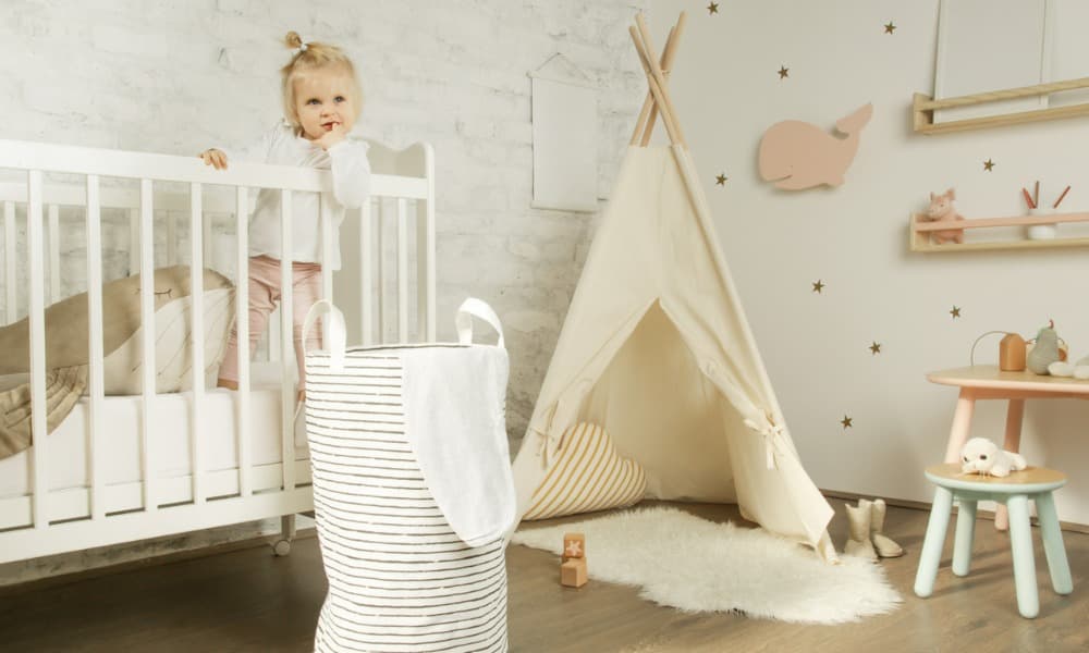 A baby girl standing in the crib in her nursery